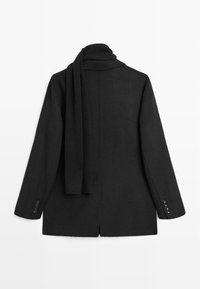 Blazer nero a maniche lunghe con sciarpa abbinata appoggiata sulla schiena, su sfondo bianco.