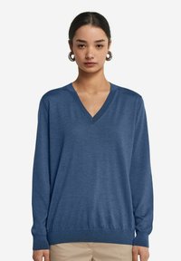 Niebieski sweter w serek wykonany z miękkiego dzianiny, z długimi rękawami i ściągaczami, zapewniającym luźny krój.