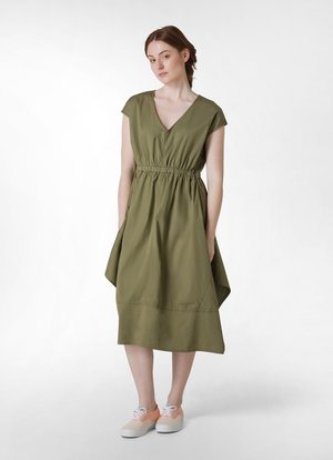 Abito verde oliva, lungo fino al ginocchio, con scollatura a V, maniche corte e vita elastica. Abbinato a sneakers pastello. Tessuto morbido, design casual.