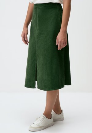 Groene corduroy midi-rok met een voornaad, rechte snit, zachte textuur en afgewerkte onderkant. Gecombineerd met witte sneakers.