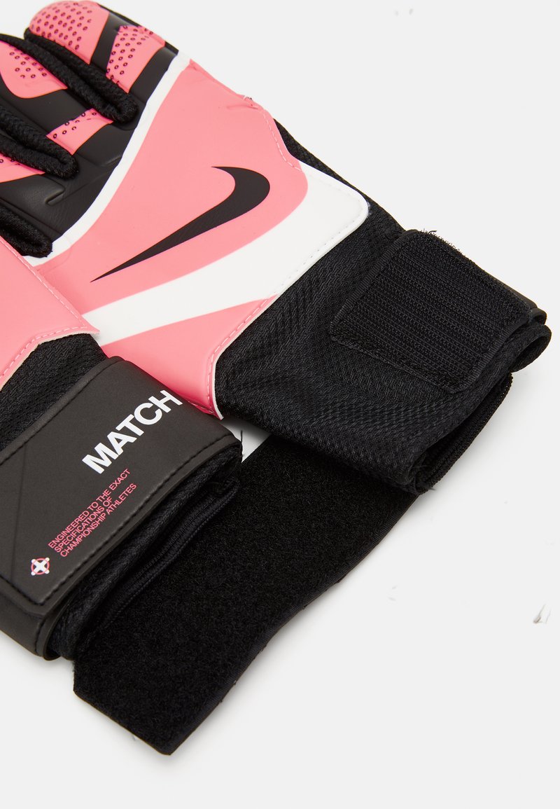 Różowe rękawice bramkarskie do piłki nożnej z czarno-białymi akcentami. Posiadają teksturowany chwyt i regulowany pasek Velcro, oznaczone napisem "MATCH" na mankiecie.