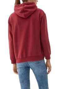 Sweat à capuche bordeaux en mélange de coton, avec capuche à cordon de serrage, poignets et ourlet côtelés ; associé à un jean denim bleu clair.
