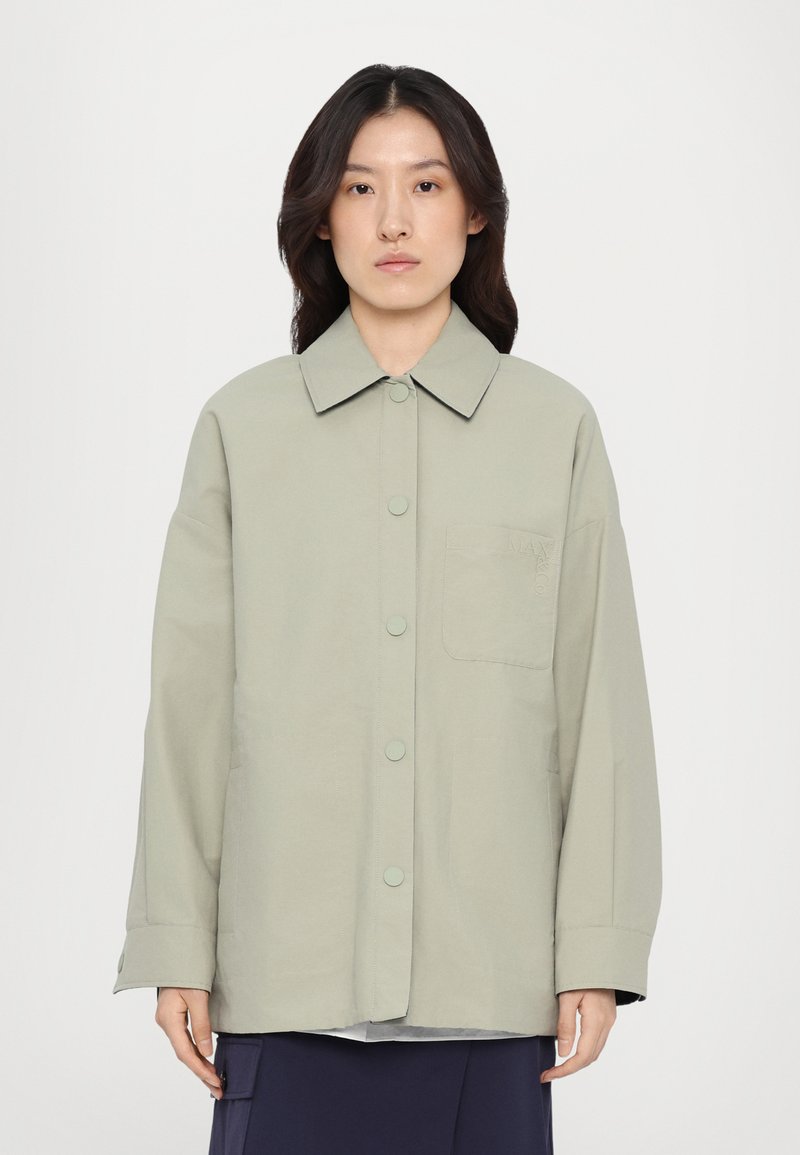 Light green oversized shirt jacket, featuring a pointed collar, front buttons, side pockets, and a subtle chest pocket detail.