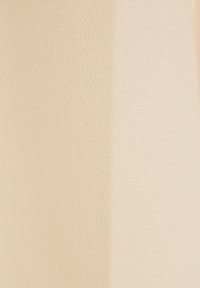 Persikofärgad texturerad tyg med en slät yta, som uppvisar en lätt glans och subtila variationer i nyans över materialet.