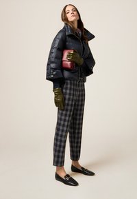 Granatowa puchówka, szare spodnie w kratę, ciemnozielone rękawiczki, czarne mokasyny. Czerwona torebka oraz wzorzysta chusta dopełniają stylizację.