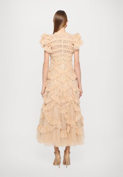 Robe en tulle pêche pâle avec des volants superposés, des embellissements scintillants, des manches bouffantes courtes et une jupe évasée. Vue de dos.