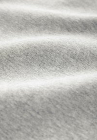 Tissu gris avec une surface douce et texturée, présentant des variations subtiles de teinte et une apparence lisse et ondulée.