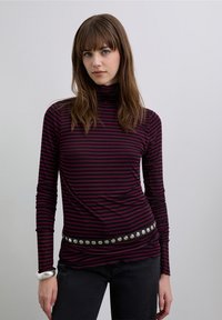 Long-sleeve turtleneck top in dark red and black stripes, featuring a fitted design and a glossy black belt with metal studs.