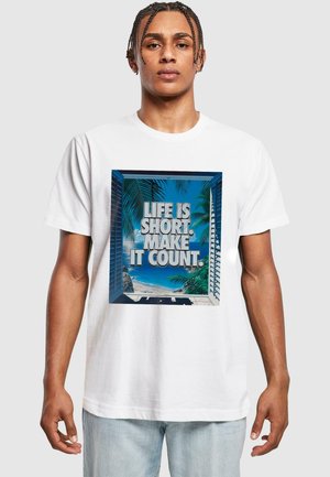 Hvit T-skjorte med grafisk trykk som har teksten "LIVET ER KORT. GJØR DET TELT." og en strandscene innrammet av blå persienner.