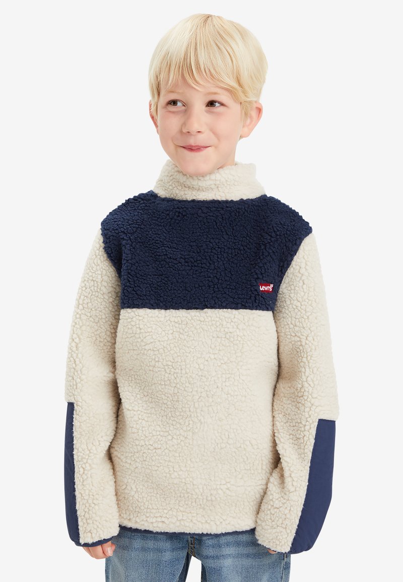 Sudadera de forro polar en beige y azul marino, con cuello alto, textura suave y logo de Levi's en el pecho. Puños y mangas acanalados.