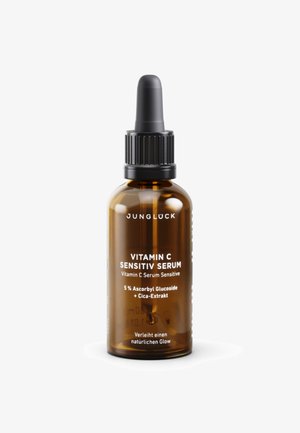 Bernsteinfarbene Glasflasche mit Pipettenaufsatz. Weiße Etiketten weisen auf "Vitamin C Sensitiv Serum" und die Inhaltsstoffe hin. Schlankes, abgerundetes Design.