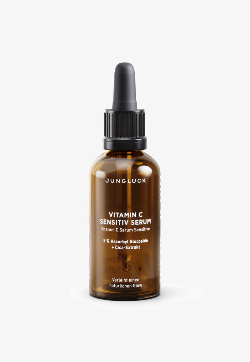 Amber glass bottle with a dropper top. White text labels indicate "Vitamin C Sensitiv Serum" and ingredients. Sleek, rounded design.