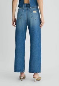 Laiad sinised denim teksad kergelt pleekinud pesuga, kõrge vöökohaga, nelja taskuga ja bränditud tagaplaadiga.