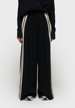 Pantaloni larghi neri realizzati in un tessuto morbido, con strisce laterali color crema lungo la lunghezza e una vita elasticizzata per il massimo comfort.