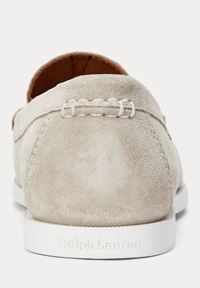 Mocasins de camurça em bege claro com sola de borracha branca. Apresentam detalhes costurados e nome da marca em relevo no calcanhar.