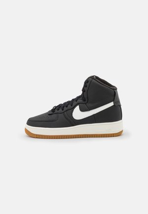 Czarny but typu high-top z białym logo Nike, białą podeszwą i gumową podeszwą zewnętrzną, pokazany z boku na białym tle.