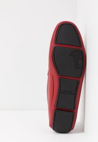 Rotes Leder-Schuhsohle mit einer strukturierten schwarzen Gummi-Basis. Mit eingestampedem Versace-Logo und detaillierten Nähten entlang der Kanten.