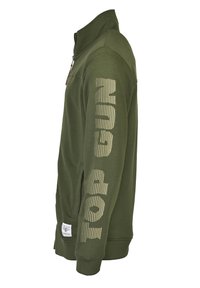 Zielona bluza z wysokim kołnierzem, z przodu na zamek, z długimi rękawami i napisem "TOP GUN" wydrukowanym dużą, teksturowaną czcionką na prawym rękawie.