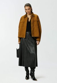 Smeđi pamučni kaput s četiri džepa, crni pleteni top, crna kožna midi suknja i crne čizme s potpeticama, ovalnim prstima i zlatnim detaljima.