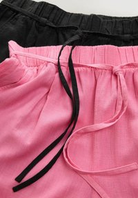 Roze en zwarte shorts met elastische taillebanden, voorzien van trekkoorden. De stof lijkt lichtgewicht met een licht gekreukte textuur.