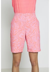 Roze korte broek met oranje abstract patroon, elastische tailleband, gedragen met een koralen textuur mouwloze top, zichtbaar van taille tot halverwege de dij.