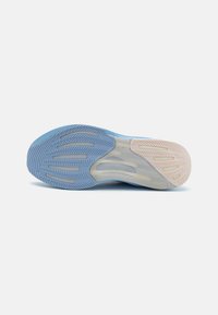 Semelle de chaussure présentant un schéma de couleurs bleu et crème, des motifs texturés, un matériau en caoutchouc avec des rainures pour la traction et une finition lisse.