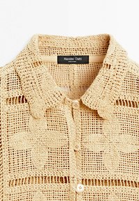 Beige gehaakte trui met bloemmotieven, knoopsluiting en een kraag, gelabeld Massimo Dutti, gemaakt in India.