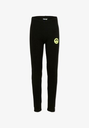 Pantalon ajusté noir avec un petit visage souriant jaune muni de crocs de vampire sur la partie supérieure droite de la cuisse, taille élastique visible à l'intérieur.