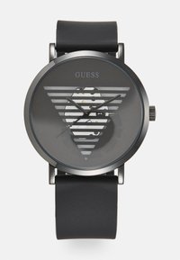 Black watch with a round case, grey dial featuring horizontal stripes and a logo. Silicone strap, metallic accents, and a minimalist design.