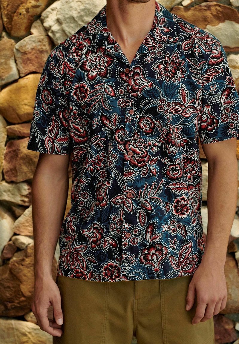 Kurzarmhemd mit dunkelblauem Blumenmuster und roten sowie weißen Akzenten, aus leichtem Stoff gefertigt und mit lockerer Passform.