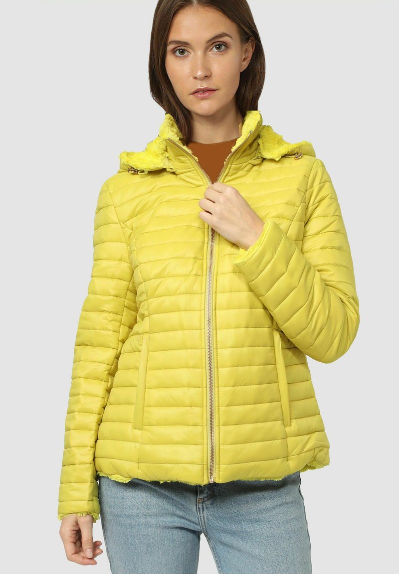 Chaqueta acolchada amarilla con capucha de piel sintética. Cuenta con cierre de cremallera y bolsillos laterales. Acabado texturizado con costuras horizontales.