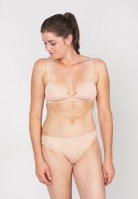 Naakt bikini-set met een driehoekige bralette en lage broekjes. Glad, rekbaar materiaal, minimalistisch ontwerp en verstelbare straps.