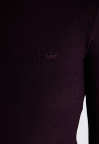 Maglietta a maniche lunghe bordeaux a coste con un sottile logo "Lee" ricamato nello stesso colore, realizzata in tessuto elasticizzato per un look aderente.