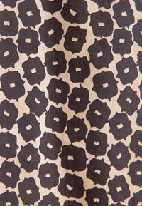 Tessuto beige con motivo floreale quadrato irregolare nero, caratterizzato da un piccolo quadrato ritagliato al centro, creando un aspetto astratto moderno.