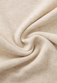 Morbido tessuto di maglia beige intrecciato per formare un morbido vortice, evidenziando la sua texture e il motivo della trama.