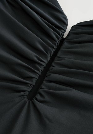 Tessuto nero con trama arricciata, caratterizzato da un'apertura a forma di V al centro. Materiale liscio, elastico con una finitura opaca.