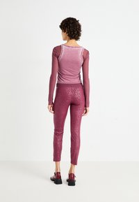 Haut mauve à manches longues avec un col rond et leggings bordeaux ajustés à motif léopard subtil, associés à des chaussures brillantes.