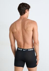 Schwarze Nike Boxer-Briefs mit einem weißen Taillengummi, auf dem das Nike-Logo zu sehen ist. Der Stoff wirkt glatt und enganliegend, entworfen für Komfort.