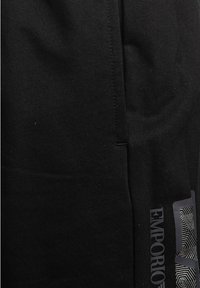 Shorts neri in cotone con una texture a coste, spacco laterale e grafica stampata "Emporio" con un motivo geometrico in basso a sinistra.