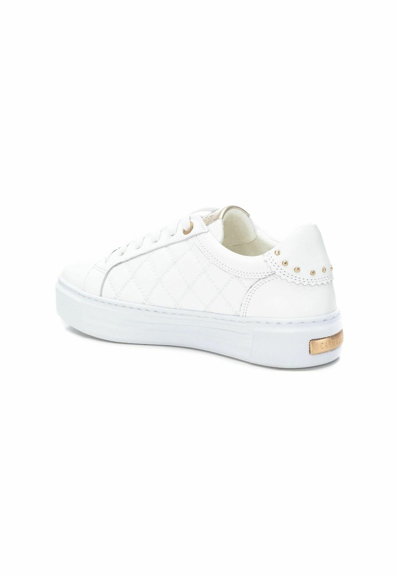 Sneaker en cuir blanc avec un motif matelassé, bout rond et semelle épaisse blanche. Présente des accents dorés sur les œillets et un logo à l'arrière.