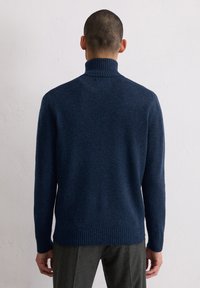 Navyblauer, gerippter Rollkragenpullover aus strukturiertem Strick mit langen Ärmeln und enger Saum, von hinten gezeigt.