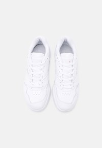 Baskets athlétiques blanches avec une tige en cuir lisse, un bout arrondi, un laçage à l'avant, des accents perforés et un col rembourré pour le confort.