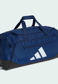 Borsa da viaggio blu navy con base nera, realizzata in tessuto resistente, dotata di manico superiore, due tasche con cerniera e grande logo bianco.