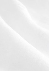 Fehér anyag sima textúrával, enyhe gyűrődésekkel. Az anyag könnyűnek és áttetszőnek tűnik, ami fokozza légies jellegét.