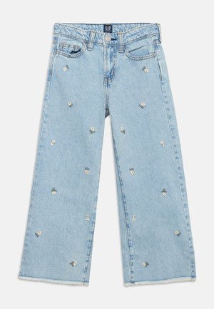 Jean en denim bleu clair à jambes larges avec petites broderies de marguerites blanches dispersées et bords bruts.