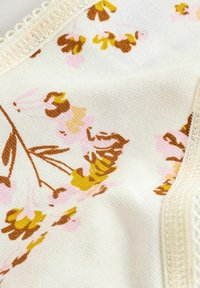 Tessuto a fantasia floreale con fiori gialli, marroni e rosa su uno sfondo crema, con una delicata rifinitura in pizzo lungo il bordo.