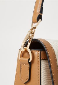 Tan leather handbag with a gold metal clasp, featuring a striped textile design and contrasting black accents on the strap and edges.