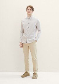 Lichtgekleurde overhemden met een geometrisch patroon, gecombineerd met beige broeken en tan sneakers. Gladde textuur, op maat gemaakte pasvorm.