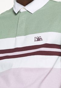 Polo w paski w kolorach zielonym, białym i liliowym, wykonany z bawełny, z białym kołnierzykiem oraz haftowanym bordowym logo na piersi.