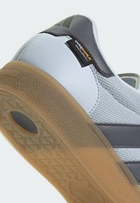 Lichtblauwe sneaker met een bovenwerk van textuurleer, grijze accenten en een rubberen zool met een patroon voor grip. Cordura-logo zichtbaar.
